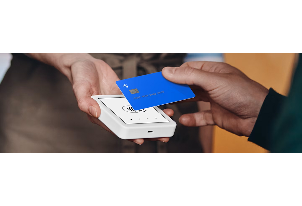 Απεικονίζεταιπελάτης να περνάει την κάρτα του σε POS που κρατάει ένα άλλο άτομο.